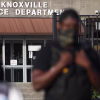 A Black police officer outside the Knoxville Police Department as a demonstrator speaks.