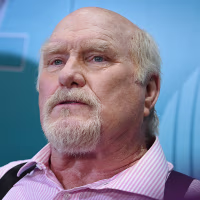Terry Bradshaw seated in front of a blue backdrop.