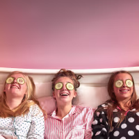 Girls wearing cucumber slices on eyes in bed