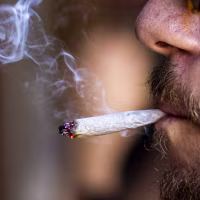 Close up of a person's face smoking marijuana