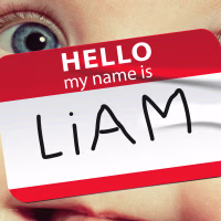 Photo illustration of a close-up of a baby's face; overlaid with a "Hello my name is Liam" sticker