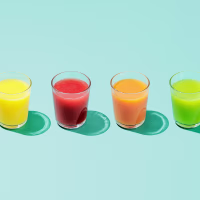 Four glasses of different colored juice on a colorful background.