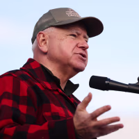 Tim Walz speaks, wearing a red plaid button up