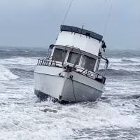 A boat is grounded on a beach by the shore
