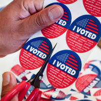 Close up on a sheet of "I Voted" stickers being cut on a table