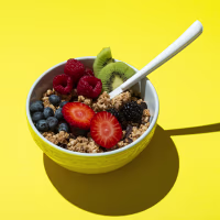 Bowl with muesli ,chocolate and fruits on on yellow background