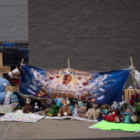A memorial with balloons and stuffed animals in front of a Walmart.