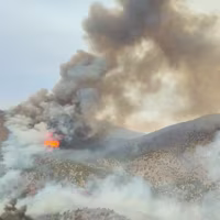 Close-up aerial video showing large billowing flames and massive plumes of smoke surrounding mountains in Eureka, Utah, on June 24, 2026.