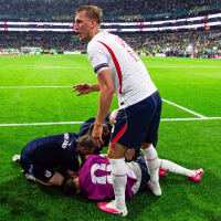 Declan Rice, left, and Dan Burn stand around Jordan Henderson who is crumpled on the ground on the soccer field