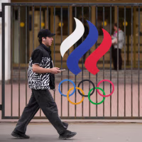 A man walks past a fence with Olympic Rings in front of the Russian National Olympic Committee building in Moscow.