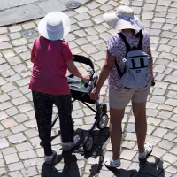 Women walking on a stone street Dresden's Old Town wearing sun hats. One woman has a walker.