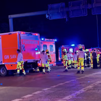Emergency workers in fluorescent safety gear in front of ambulances at night.