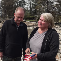 Ken, left, and Lisa Anderson stand among debris from a damaged house outside