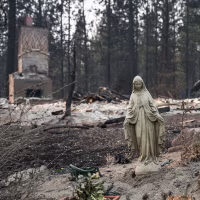 A statue of the Virgin Mary in front of a burned home in the Balboa neighborhood of Spokane, Wash., on Aug. 2, 2026.