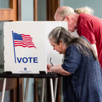 People vote at voting booths inside of a room