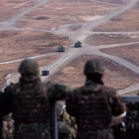 Army soldiers watch a joint live-fire exercise drill.