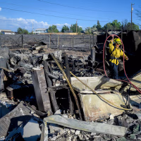 A firefighter works on the remains of a home burned by the Hawk Fire.