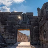 view of the Lion Gate entrance portal at the ancient citadel of Mycenae with a morning sunburst