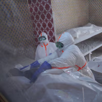Health workers prepare to transfer the body