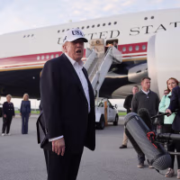 Donald Trump speaking to reporters on a tarmac.