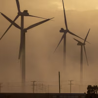 Wind turbines are partially obscured by a dust storm.