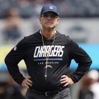 Jim Harbaugh standing with his hands on his hips on the sidelines.