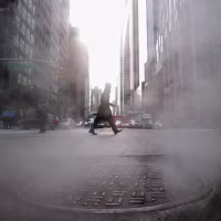 Steam rises from a sewer as a man crosses the street.