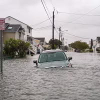 A car is seen submerged in water on a flooded road.