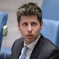 Sam Altman seated in a row of light blue upholstered chairs.