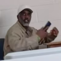 Diddy seated at a table holding a cellphone