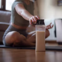 Young girl is hydrating during exercise in living room at home.