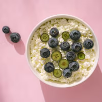 Cottage cheese with blueberry fruits on pink table in bright sunlight