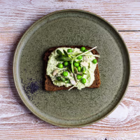 Rye bread avocado hummus dip toast with fresh green peas, sprouts, pumpkin seeds, poppy seeds