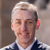 A headshot of Matthew Van Houten, standing outside