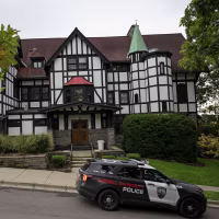 Cornell University police car passing by a fraternity house.