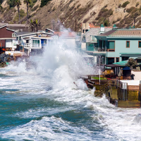 Powerful swells from Hurricane Polo, combined with a high tide, crash over protective boulders and seawalls