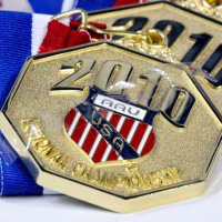 Gold medals with engraved text reading "2010 AAU USA National Championship" with an AAU crest in the center, lined up on a table