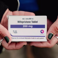 A person holding a box of mifepristone.