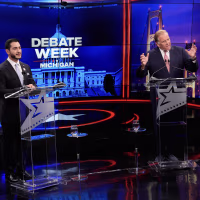 Abdul El-Sayed and Mike Rogers standing at matching lecterns during a debate.