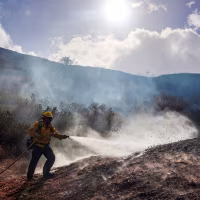 A firefighter sprays a hotspot while fighting the Bike fire
