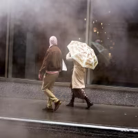 People walk in a street as the rains pours.