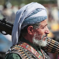 A man holds his riffle on his shoulder.
