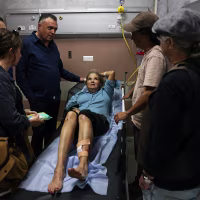 Image: Heidi Levine lies on a gurney in an emergency room of the government hospital, with a bandage on her leg.
