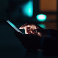 Image: Close-up of a man using a touchscreen phone.