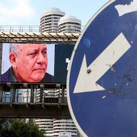 Image: A road sign stands in front of a large billboard featuring Benjamin Netanyahu and Gadi Eisenkot