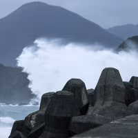Image: A woman takes pictures of waves by the coast.