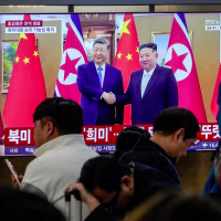 A TV screen shows a file image of North Korean leader Kim Jong Un and Chinese President Xi Jinping.