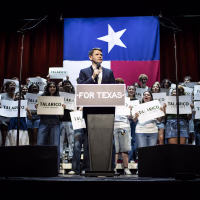 James Talarico at a podium holding a microphone and flanked by young supporters. 