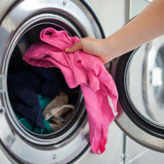 Woman putting shirt into washing machine