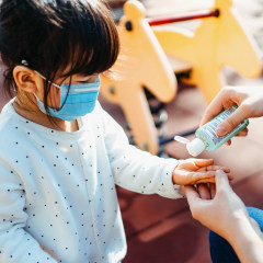 Parent applying hand sanitizer to childs hands in playground